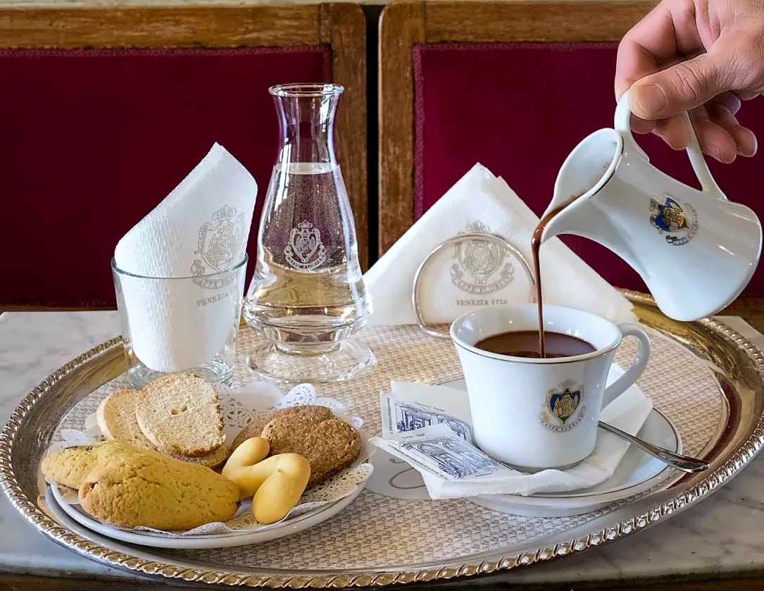 Hot chocolate poured at the table, with biscuits on a silver tray
