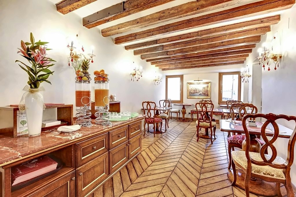 Breakfast room with wooden beams, herringbone floor and a buffet with flowers