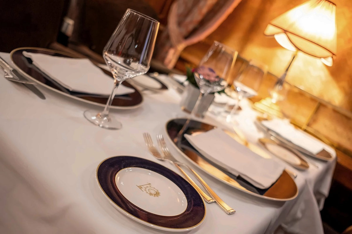 Elegant table setting with gold-rimmed plates and a warm table lamp