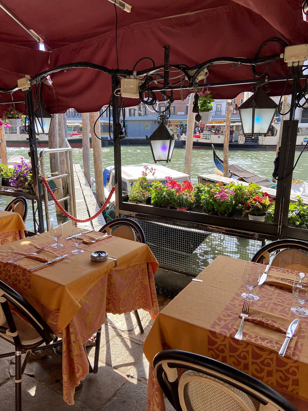 Covered terrace tables on the Grand Canal with flowers and lanterns