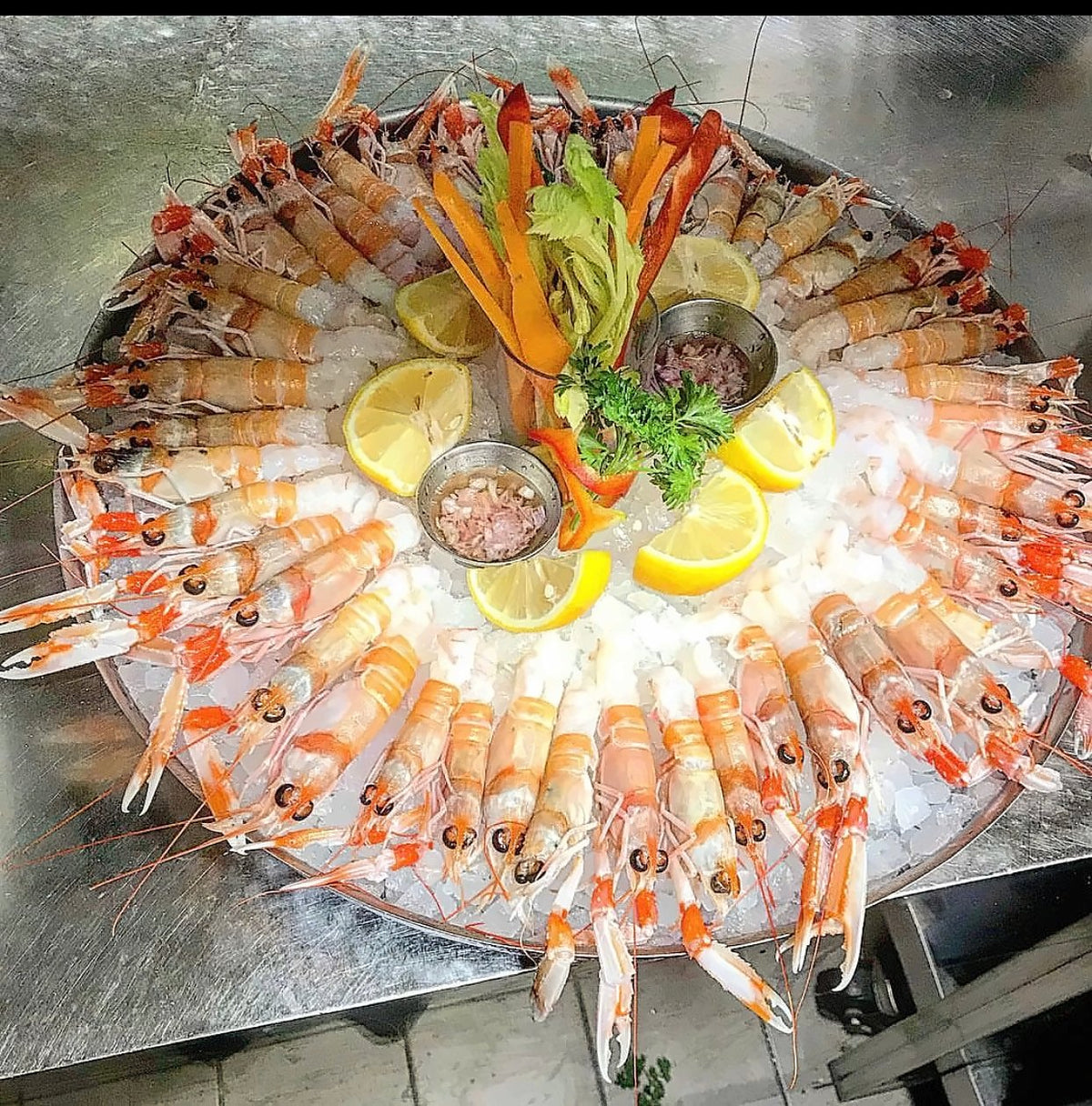 Platter of raw scampi on ice with lemon and vegetables