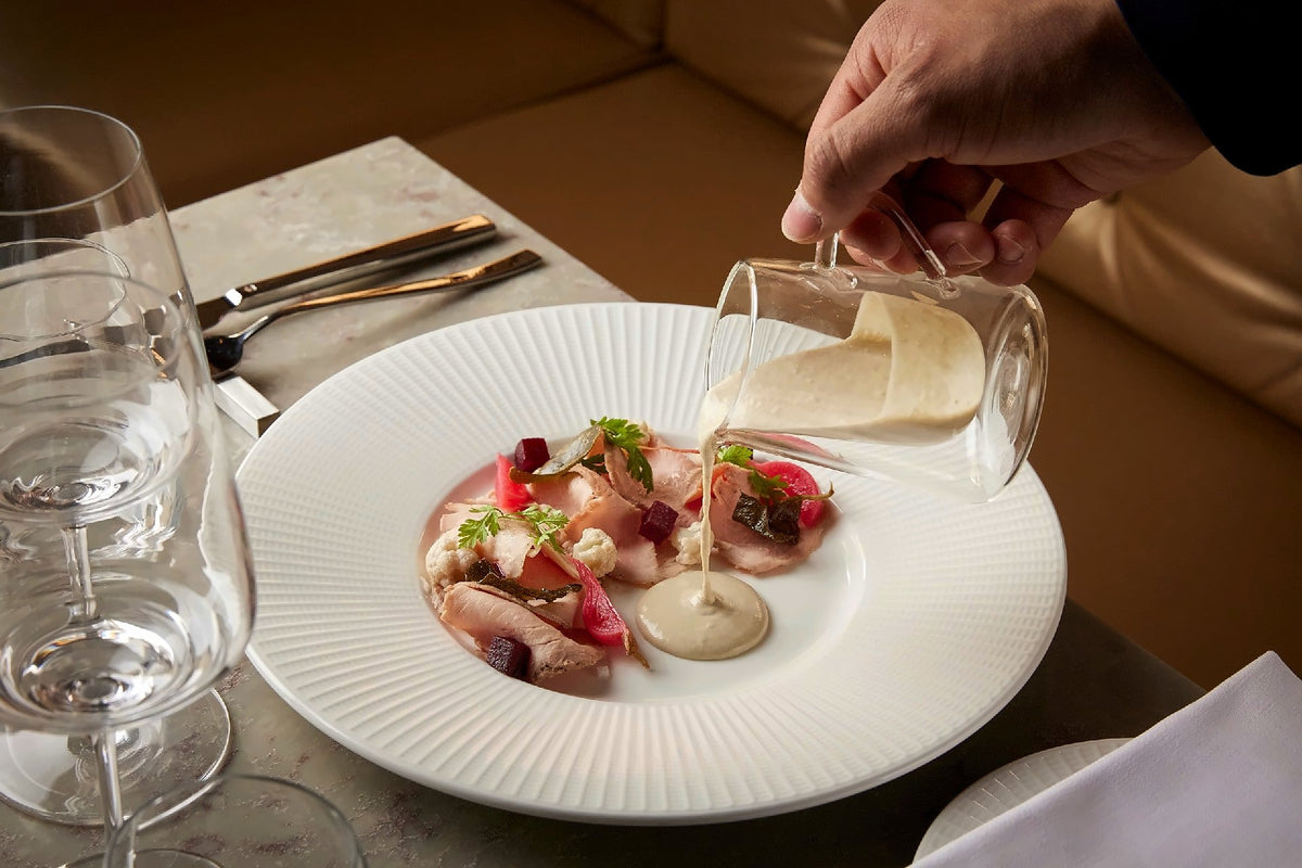 Sauce poured at the table over a plated starter with beetroot