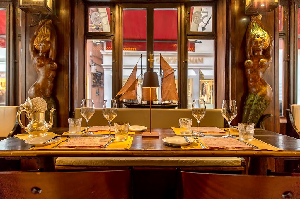 Historic dining room with carved figureheads and a model ship in the window