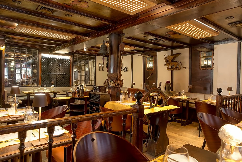 Nautical-style dining room with a ship's wheel and wooden beams