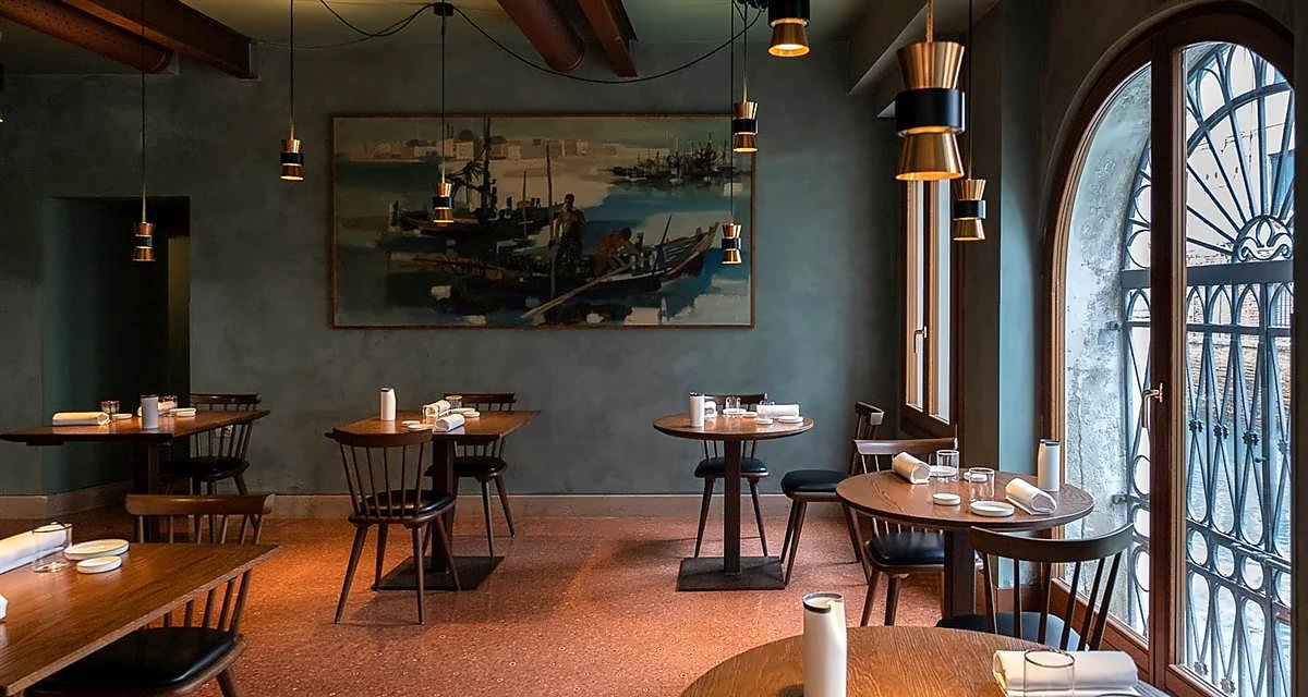 Local's dining room with wooden tables, arched windows and a lagoon painting