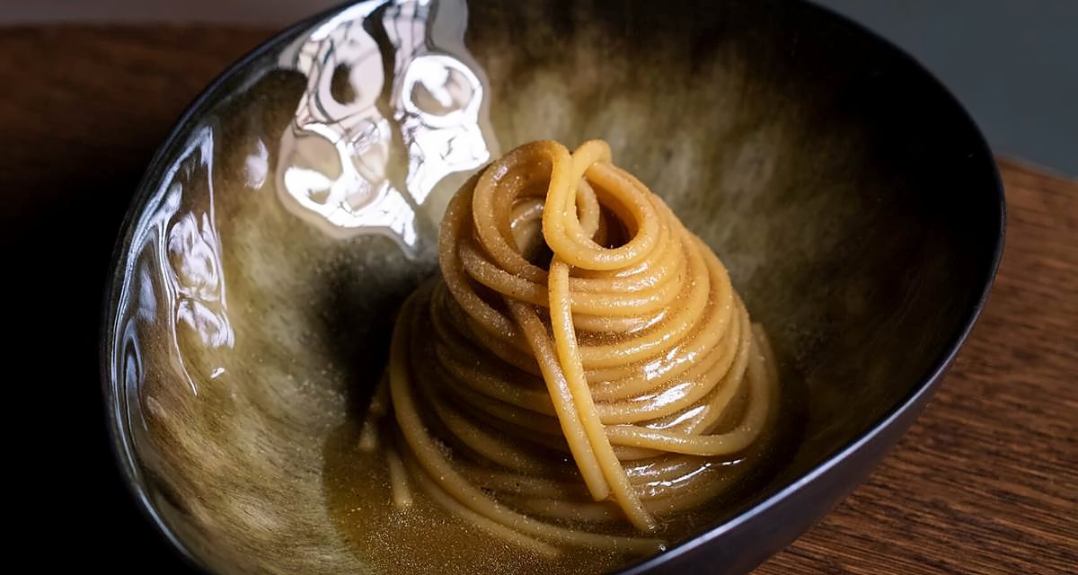 A nest of spaghetti in a dark ceramic bowl at Local