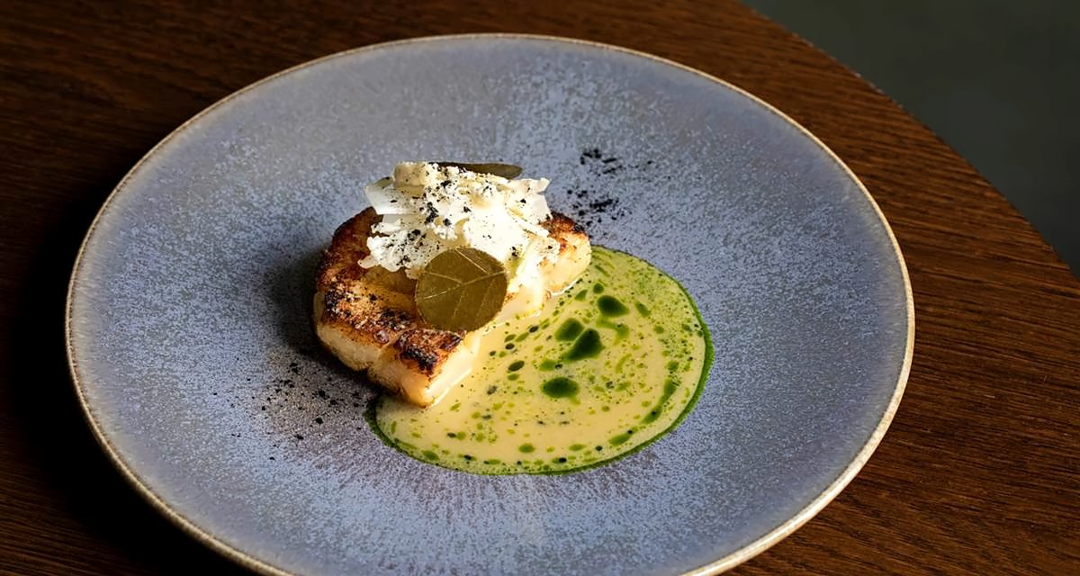 Fish fillet with green herb oil on a blue plate at Local