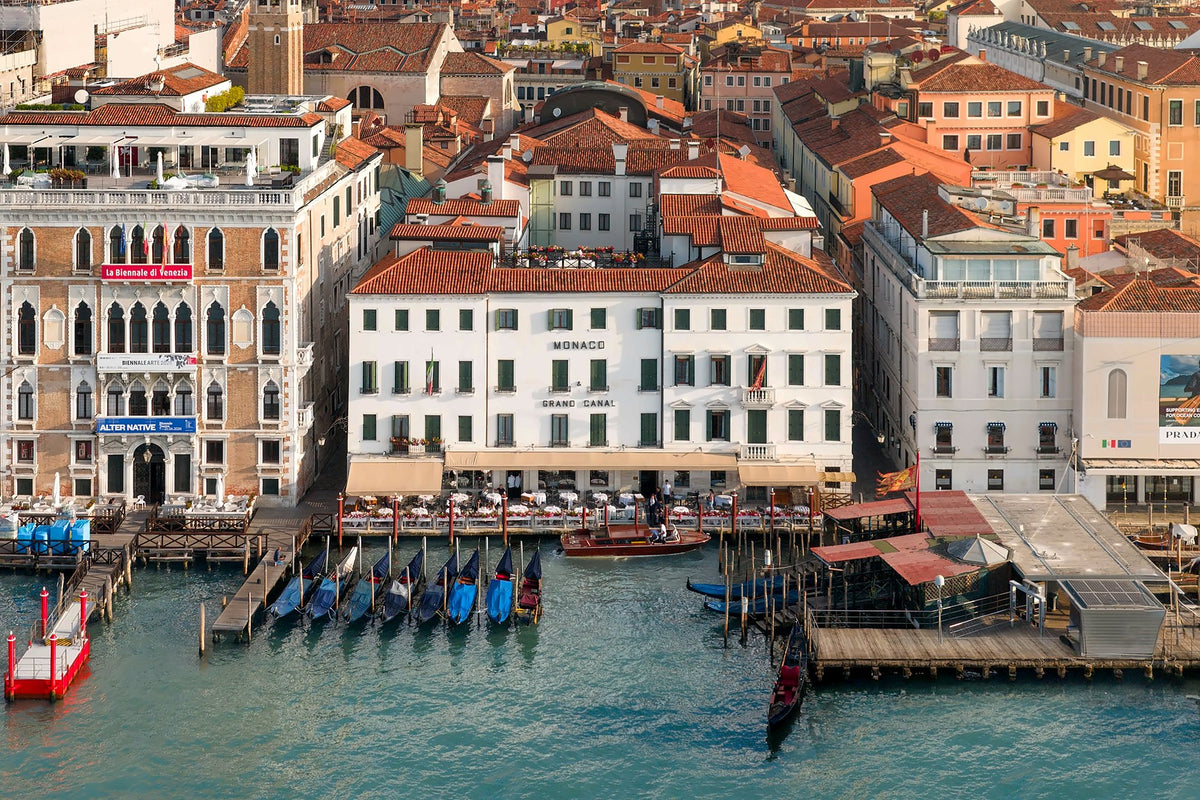 Aerial view of the hotel's white facade on the Grand Canal with moored gondolas