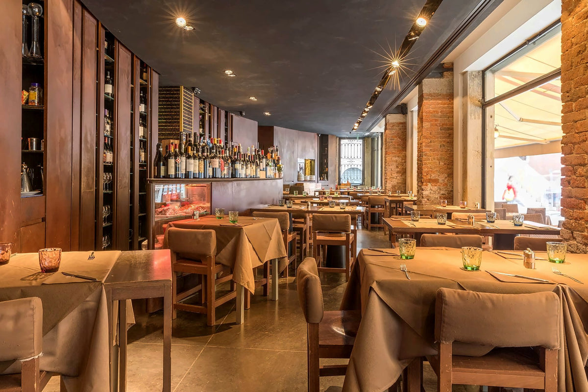 Muro Frari dining room with set tables, brick pillars and a long wine wall