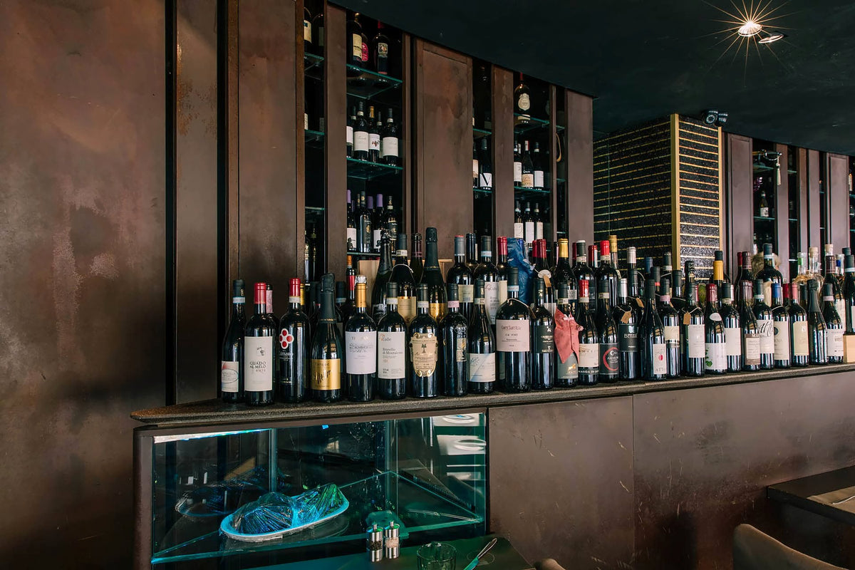 Wall of wine bottles above a display counter at Muro Frari