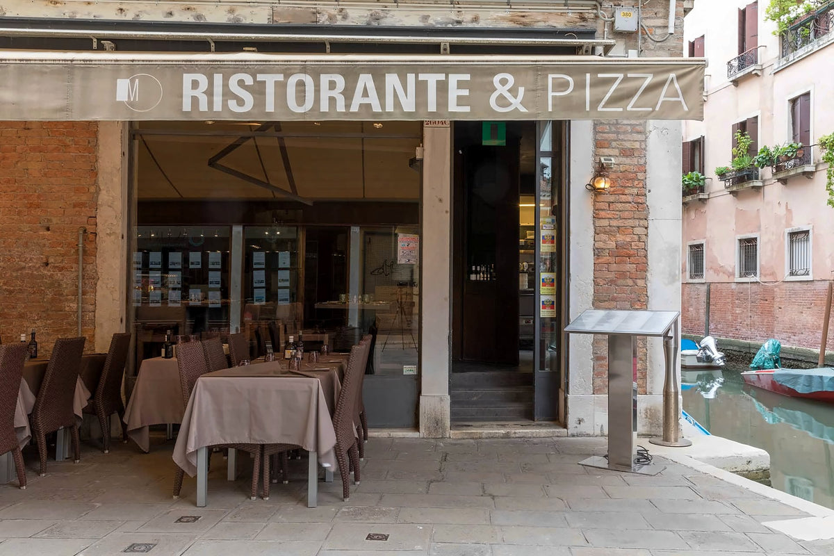 Muro San Stae entrance and outdoor tables beside a canal