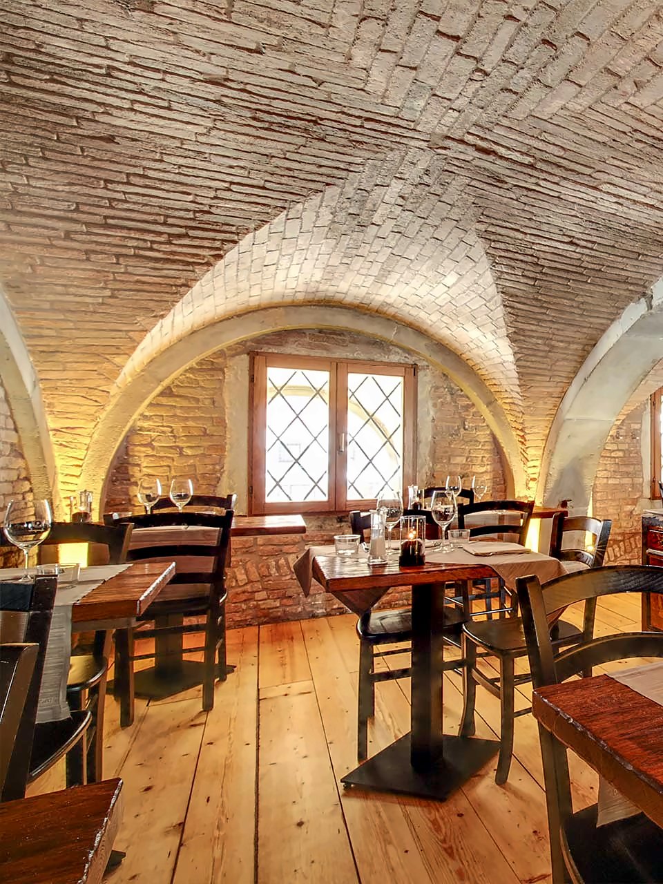Vaulted brick dining room with wooden tables at Osteria Bancogiro