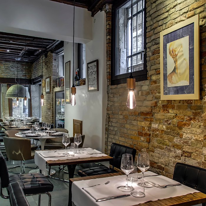Dining room with brick walls and set tables at Osteria Enoteca San Marco