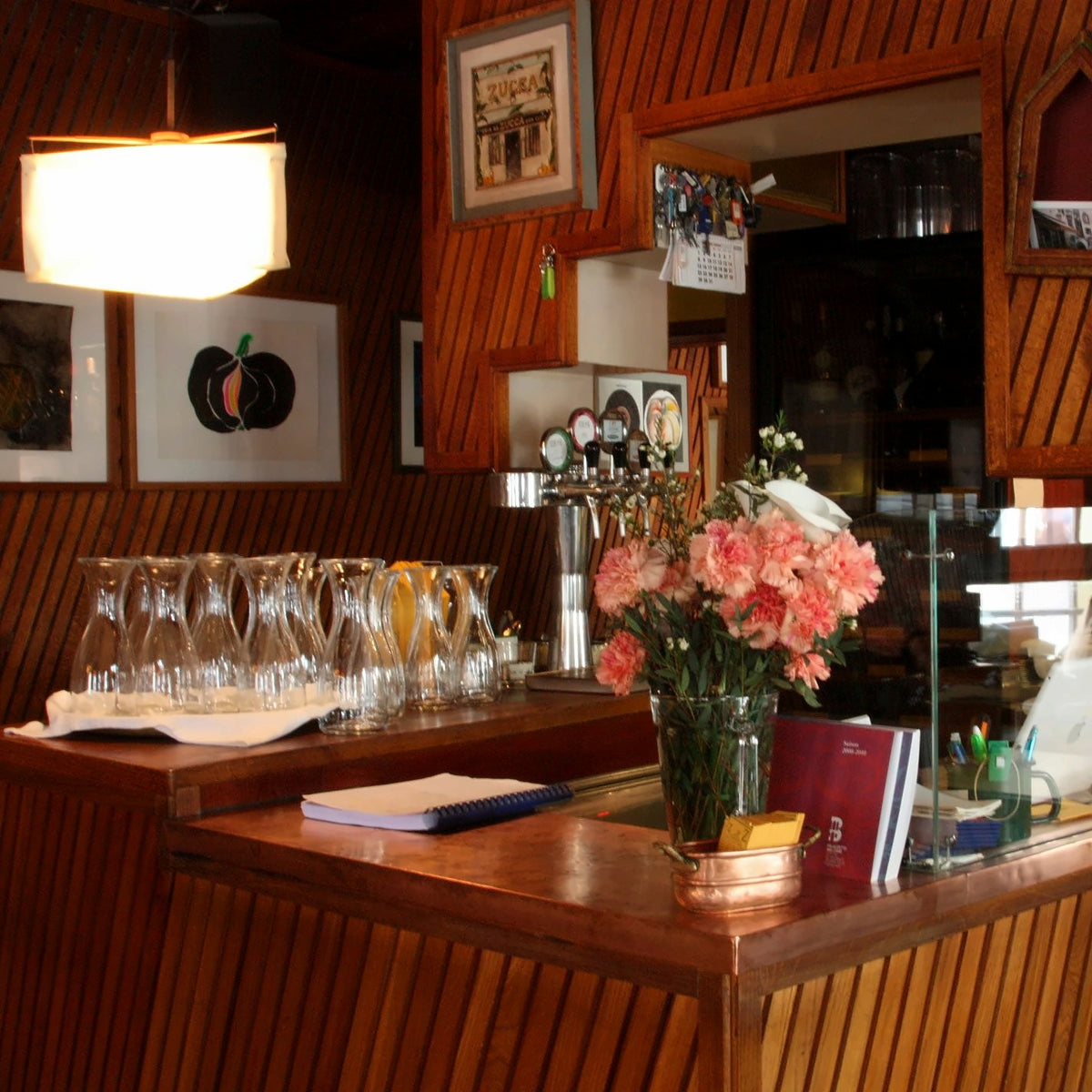 Wooden bar counter with flowers and carafes at Osteria La Zucca