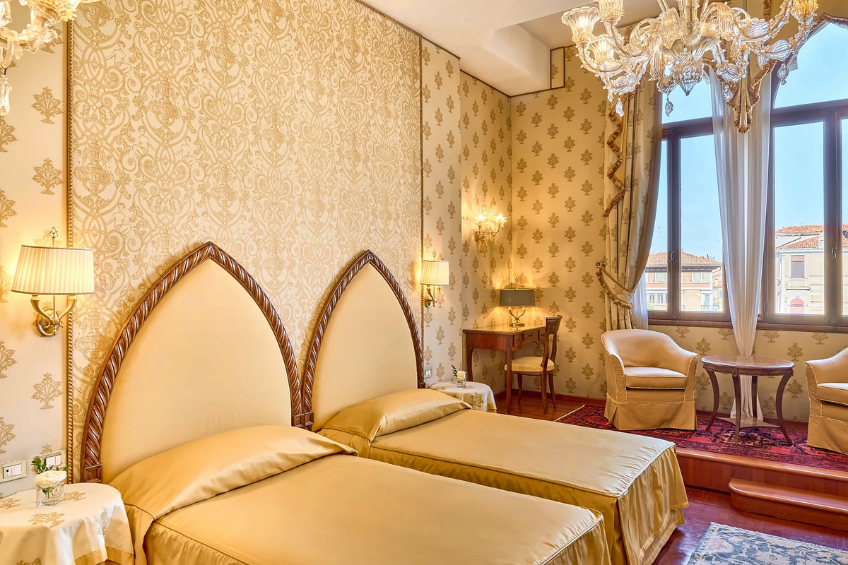Room with gilded Gothic-arch headboards, Murano chandelier and tall windows