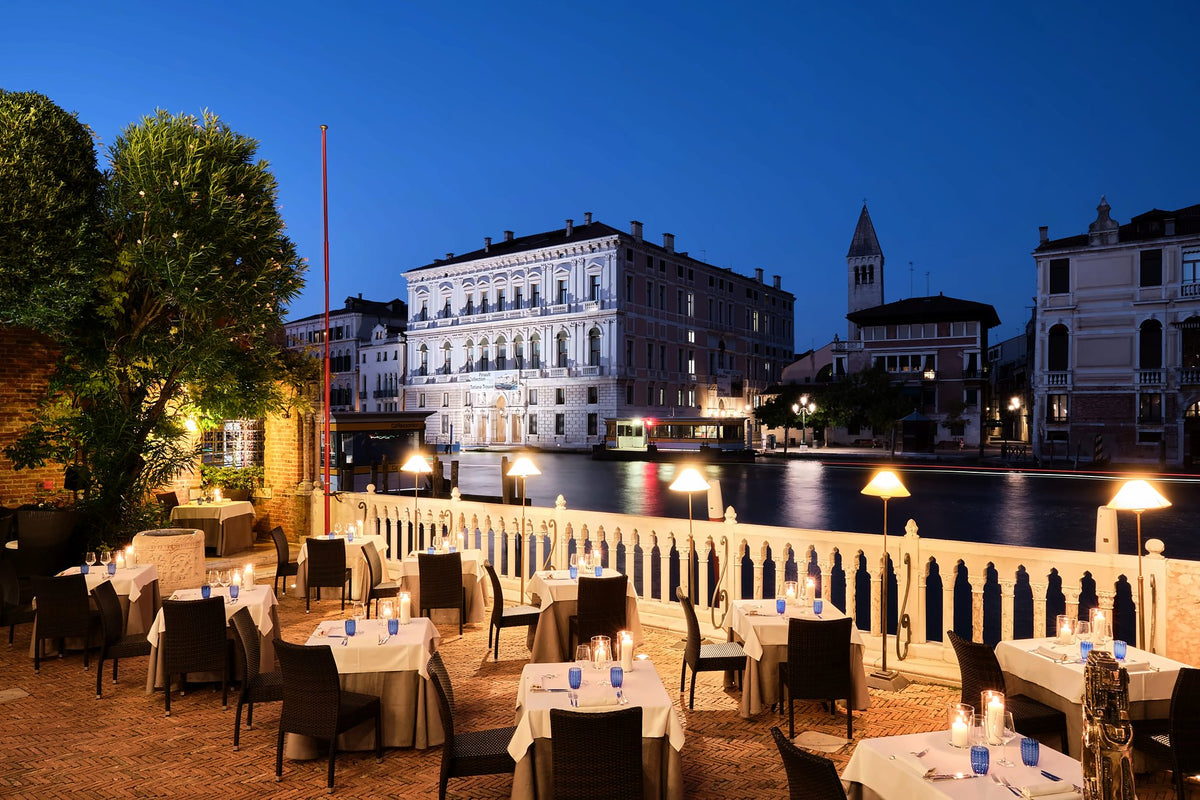 Candlelit terrace restaurant on the Grand Canal at dusk, facing Palazzo Grassi