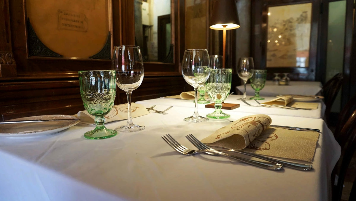 Table setting with green glasses and a small lamp at Riva del Vin