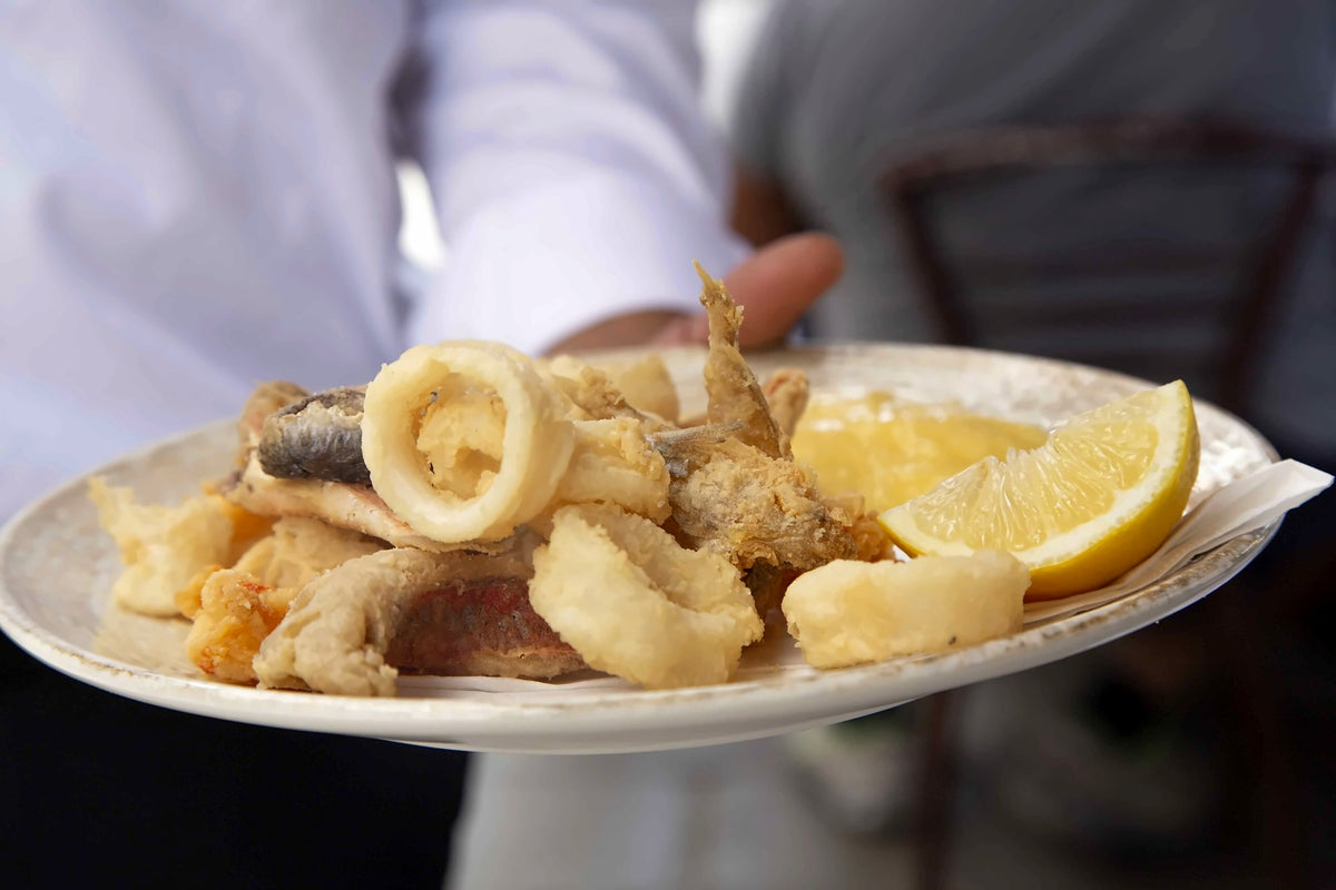 A plate of fried calamari and fish with lemon at Riva del Vin