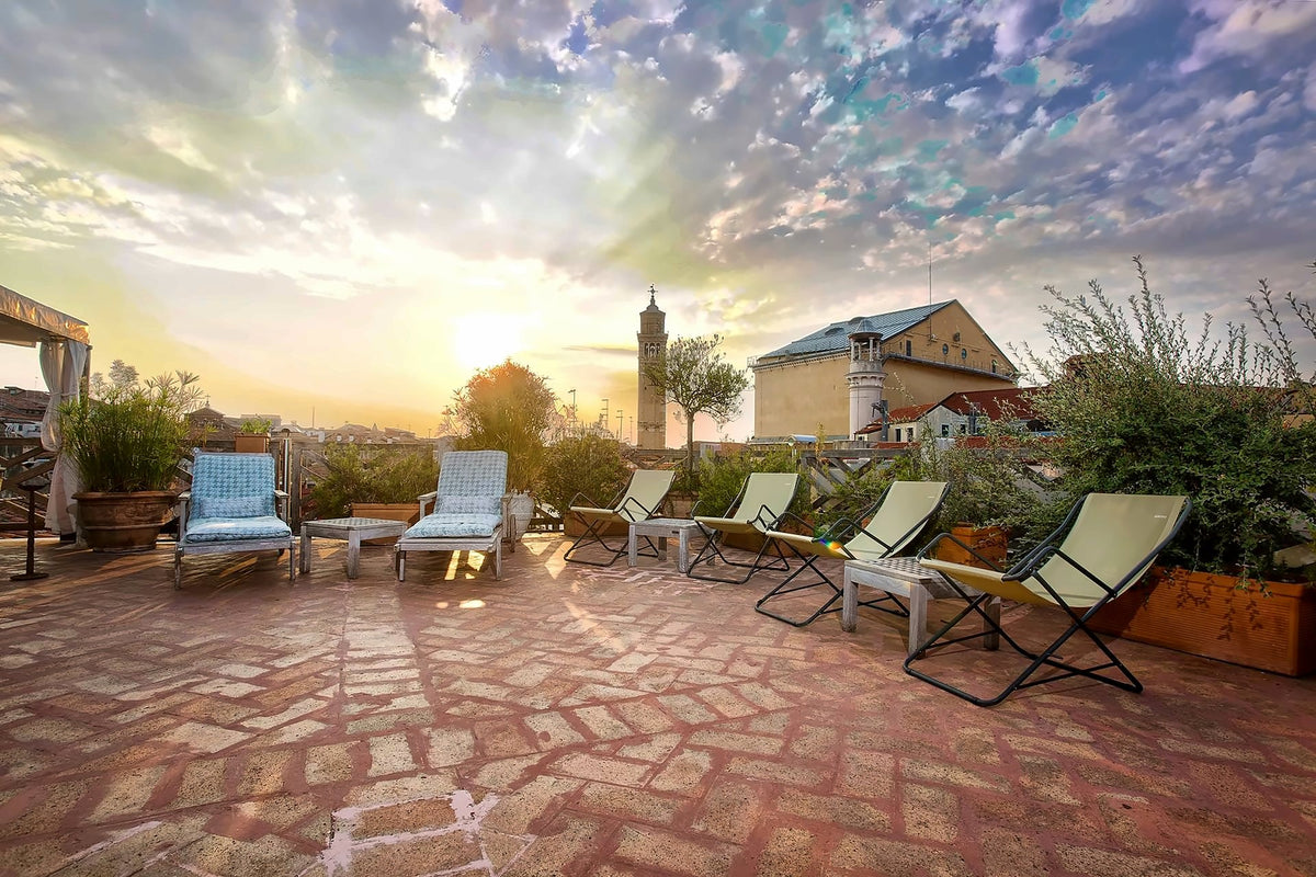 Rooftop terrace with sun loungers and a bell tower at sunset