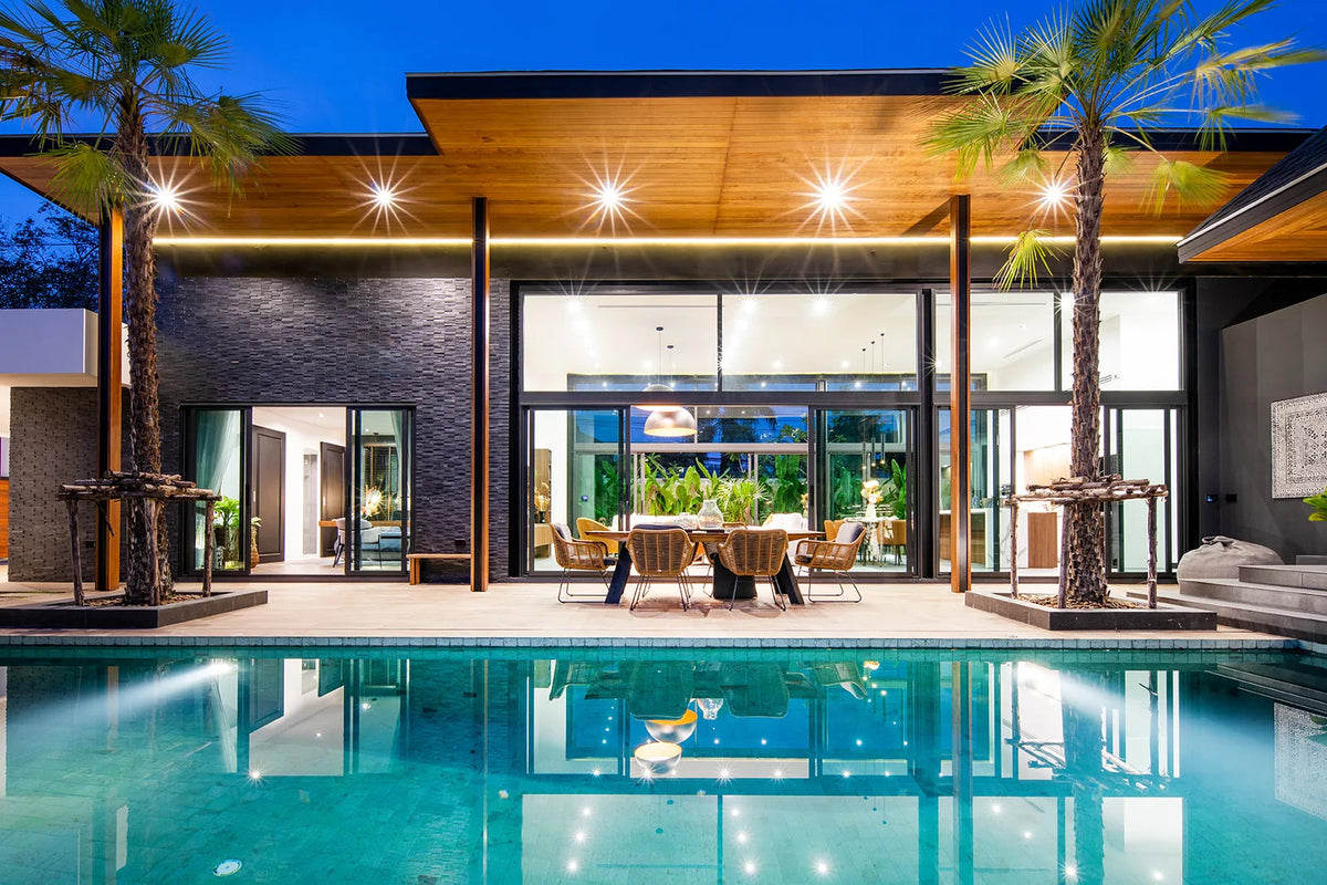 Pool villa by Suksan Homes lit up at dusk